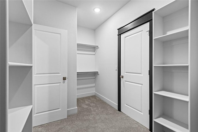 walk in closet featuring light colored carpet