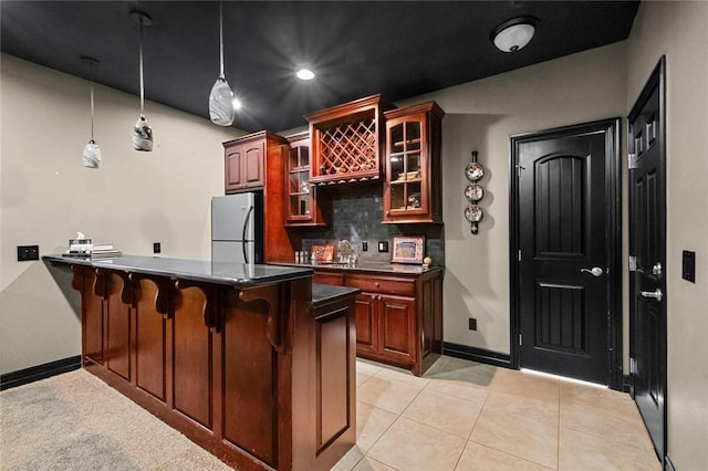 kitchen with tasteful backsplash, a kitchen breakfast bar, stainless steel refrigerator, kitchen peninsula, and light tile patterned flooring