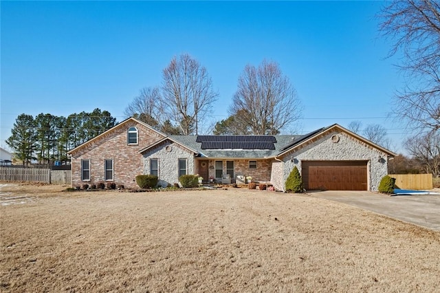 single story home with a garage and solar panels