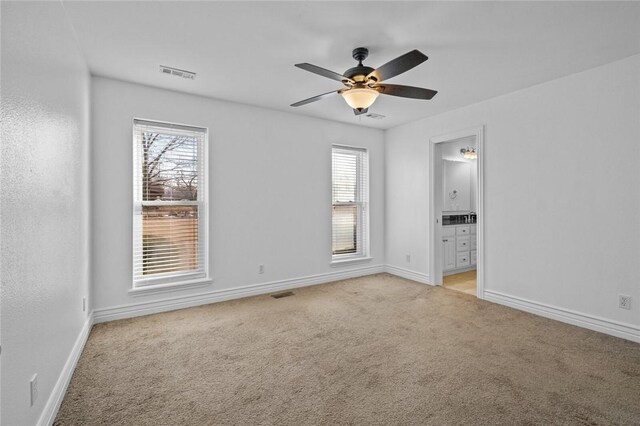 empty room featuring ceiling fan, light colored carpet, and a healthy amount of sunlight