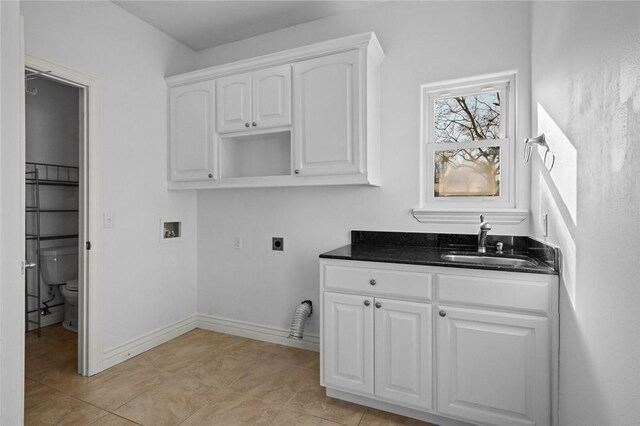 laundry area featuring cabinets, washer hookup, sink, hookup for an electric dryer, and light tile patterned floors