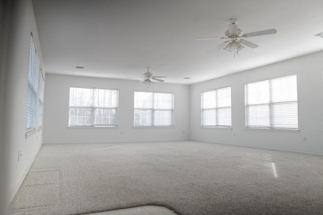 empty room with ceiling fan, light colored carpet, and a healthy amount of sunlight