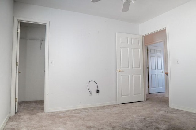 unfurnished bedroom featuring light carpet, a walk in closet, a closet, and ceiling fan