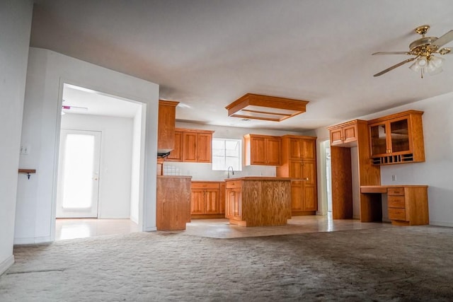 kitchen featuring light carpet, sink, built in desk, and ceiling fan