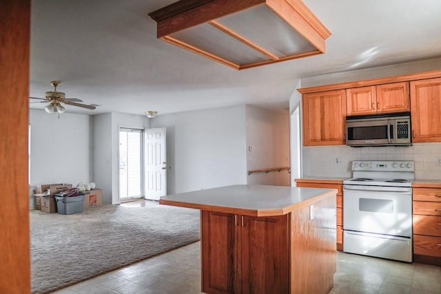 kitchen featuring ceiling fan, backsplash, white range with electric stovetop, a kitchen island, and light colored carpet