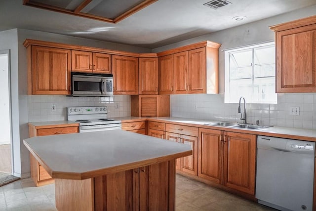 kitchen with tasteful backsplash, a kitchen island, sink, and white appliances