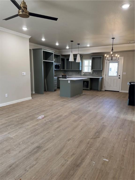 kitchen with decorative light fixtures, ceiling fan with notable chandelier, light hardwood / wood-style floors, and a center island