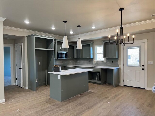 kitchen featuring an inviting chandelier, light hardwood / wood-style floors, gray cabinetry, decorative light fixtures, and a center island