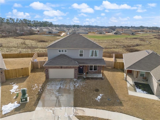 view of front of home with an attached garage, a fenced backyard, brick siding, driveway, and roof with shingles