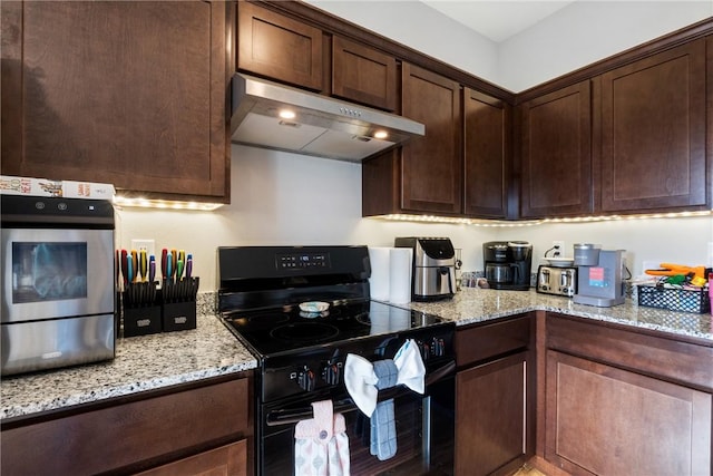 kitchen featuring oven, light stone countertops, dark brown cabinets, black electric range, and under cabinet range hood