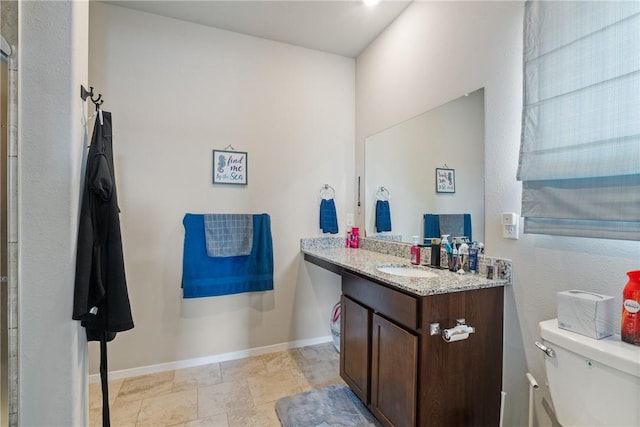 bathroom featuring toilet, baseboards, and vanity