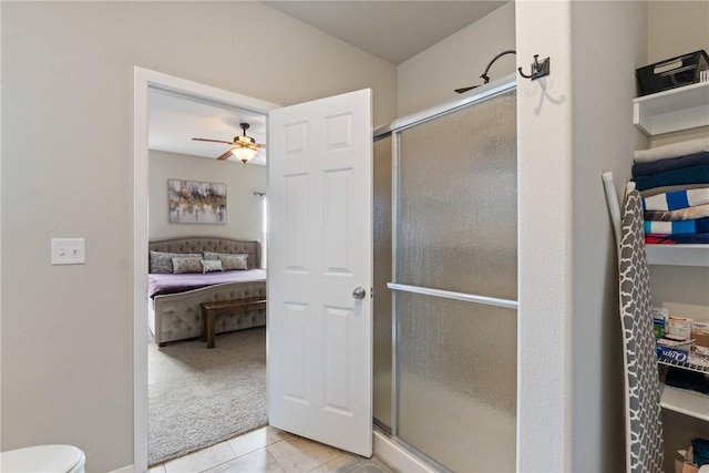 bathroom featuring ceiling fan, tile patterned floors, a shower with door, and toilet