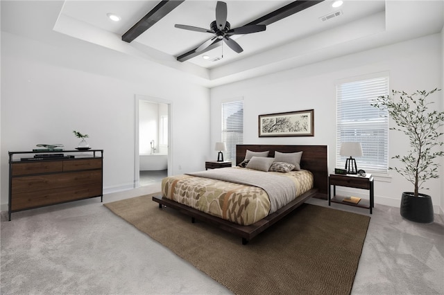 bedroom featuring light carpet, ceiling fan, connected bathroom, and a tray ceiling