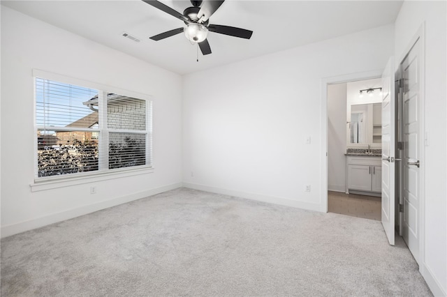 spare room featuring light carpet, ceiling fan, and sink