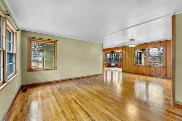 55 Ridgeway Ave, Eureka Springs, AR 72632 - unfurnished living room with light wood finished floors, healthy amount of natural light, a ceiling fan, and wooden walls