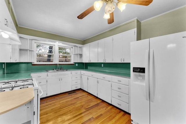 kitchen with sink, light hardwood / wood-style floors, white cabinets, and white appliances