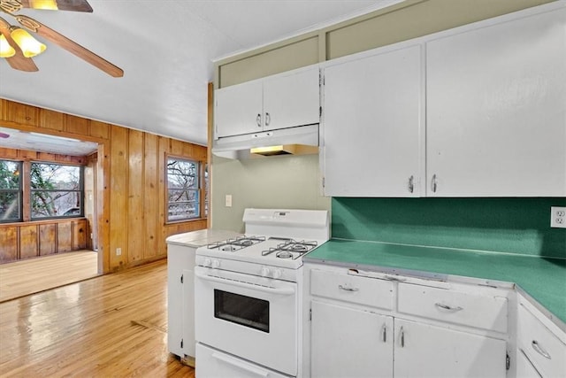 kitchen with gas range gas stove, light hardwood / wood-style floors, wooden walls, ceiling fan, and white cabinets