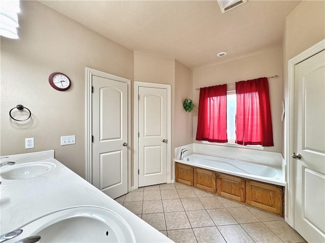 bathroom with double vanity, tile patterned flooring, a sink, and a bath