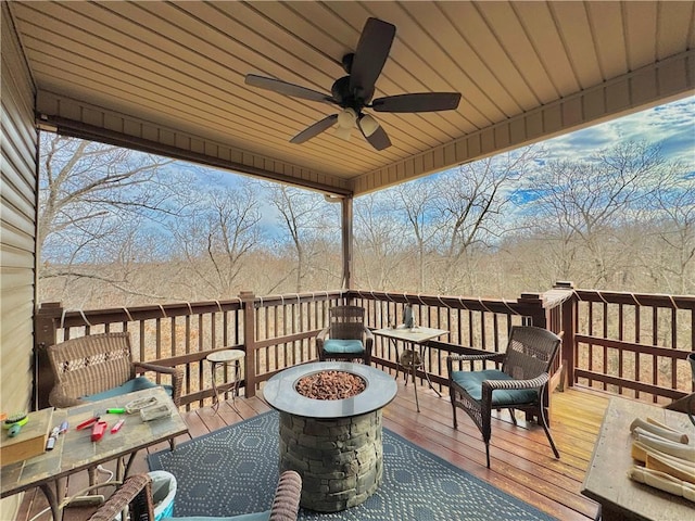 wooden deck with an outdoor fire pit, outdoor dining area, and a ceiling fan