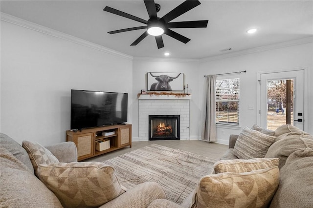 living room with ceiling fan, crown molding, and a fireplace