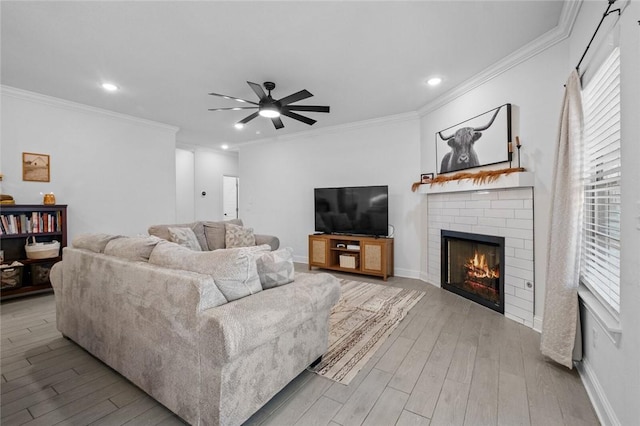 living room with a brick fireplace, ornamental molding, and light wood-type flooring