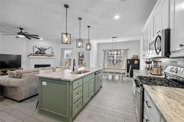 kitchen with stainless steel appliances, a kitchen island with sink, green cabinetry, white cabinets, and sink