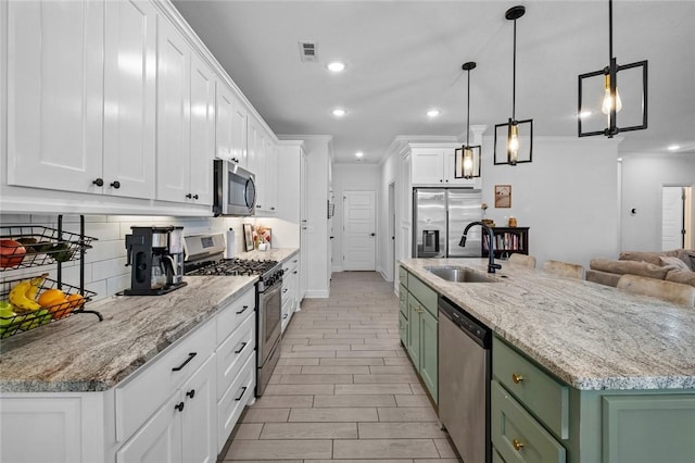 kitchen with appliances with stainless steel finishes, a center island, white cabinetry, sink, and green cabinetry