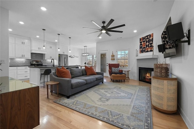 living room with ceiling fan, light hardwood / wood-style floors, and sink