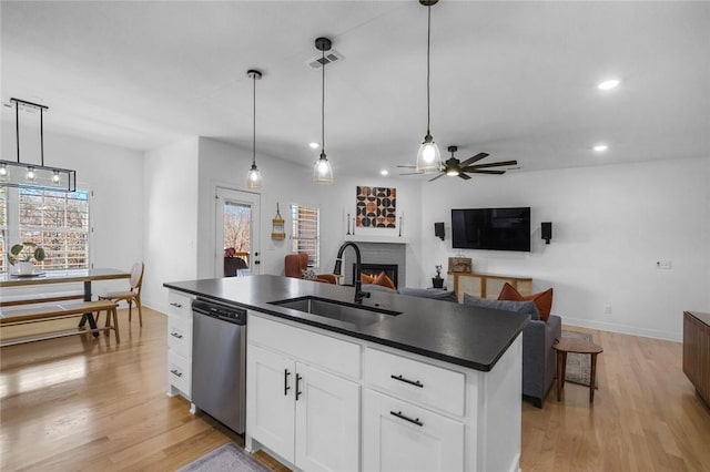 kitchen featuring white cabinetry, a kitchen island with sink, hanging light fixtures, stainless steel dishwasher, and sink