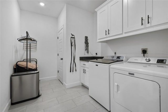 laundry area featuring washer and clothes dryer, light tile patterned floors, and cabinets