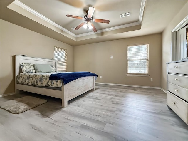 bedroom featuring ceiling fan, crown molding, light hardwood / wood-style floors, and a tray ceiling