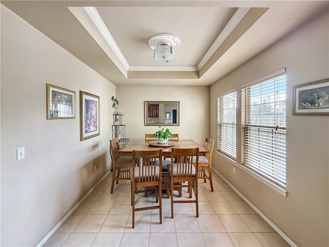 dining room featuring a raised ceiling, light tile patterned floors, and ornamental molding