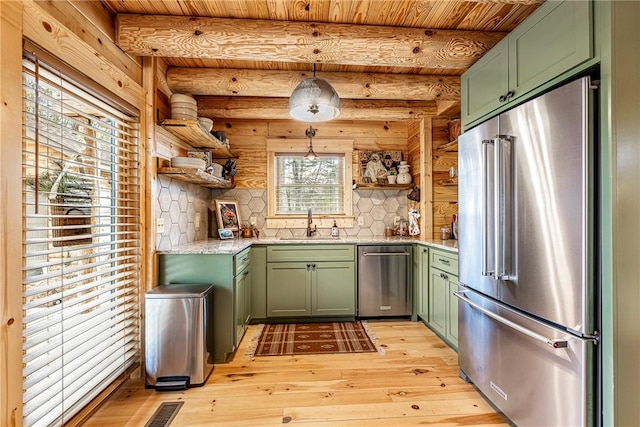 kitchen with green cabinetry, stainless steel appliances, decorative light fixtures, and light wood-type flooring