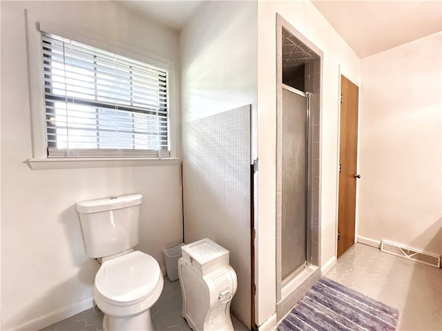 bathroom featuring toilet, tile patterned floors, and a shower with door