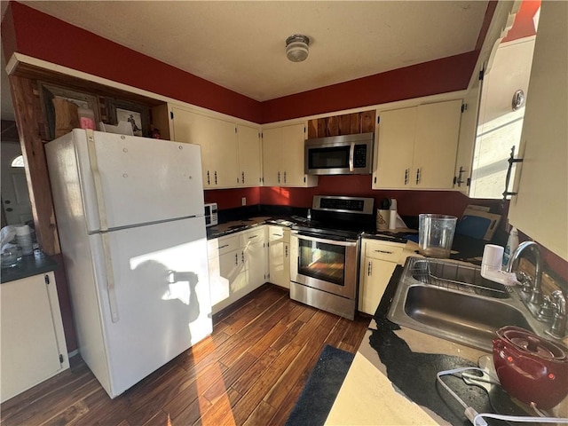 kitchen with dark wood-type flooring, sink, stainless steel appliances, and cream cabinets