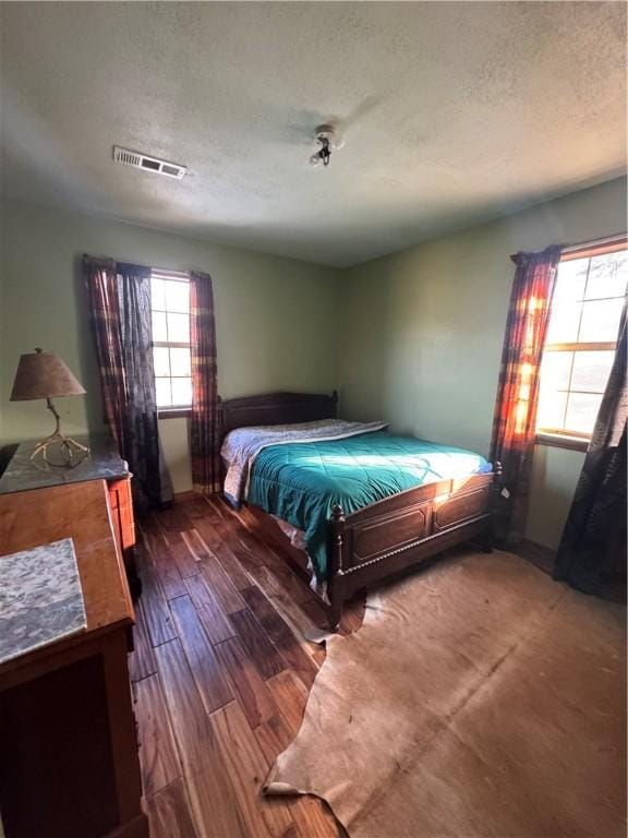 bedroom featuring a textured ceiling and dark hardwood / wood-style flooring