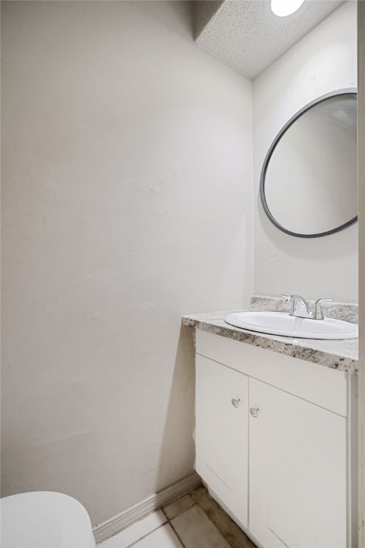 bathroom with toilet, vanity, tile patterned floors, and a textured ceiling