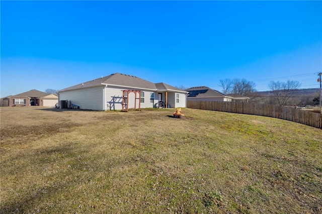 exterior space with central AC unit, fence, and a yard