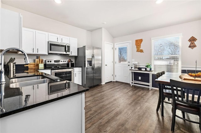 kitchen with stainless steel appliances, dark wood-type flooring, a sink, white cabinets, and dark stone countertops