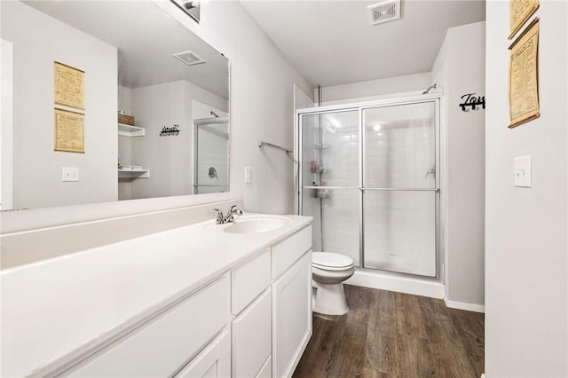 bathroom featuring wood-type flooring, an enclosed shower, vanity, and toilet