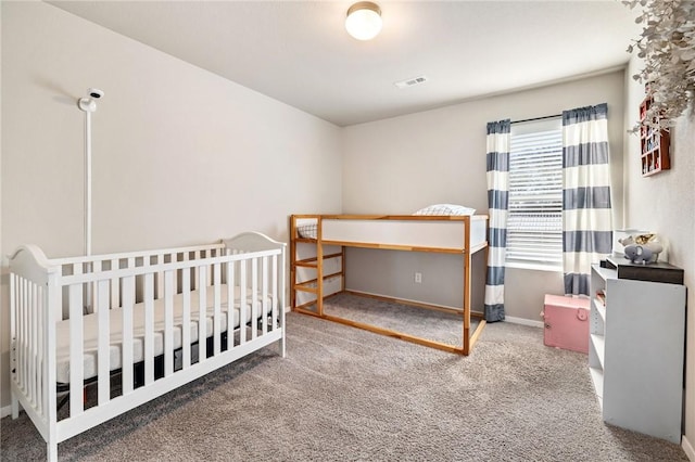 carpeted bedroom with a crib, baseboards, and visible vents