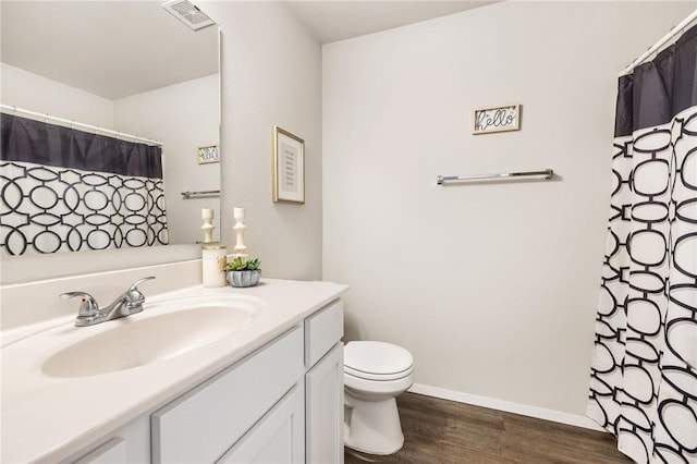 bathroom with visible vents, toilet, vanity, wood finished floors, and baseboards