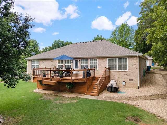 rear view of house featuring a wooden deck and a lawn