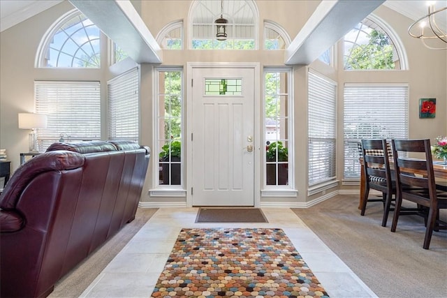 entrance foyer with a wealth of natural light, light colored carpet, a towering ceiling, and a notable chandelier