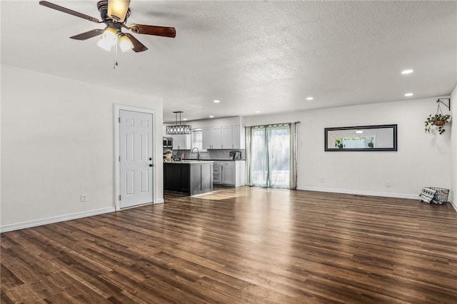 unfurnished living room featuring a textured ceiling, ceiling fan, dark hardwood / wood-style floors, and sink