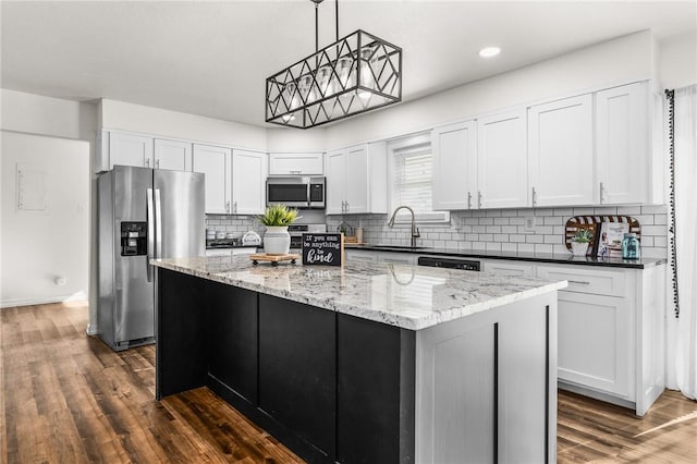 kitchen with hanging light fixtures, white cabinets, a center island, and stainless steel appliances