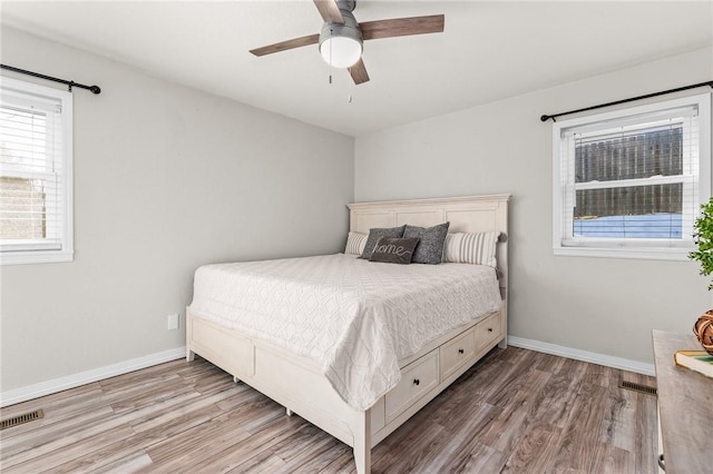 bedroom featuring ceiling fan, light hardwood / wood-style floors, and multiple windows