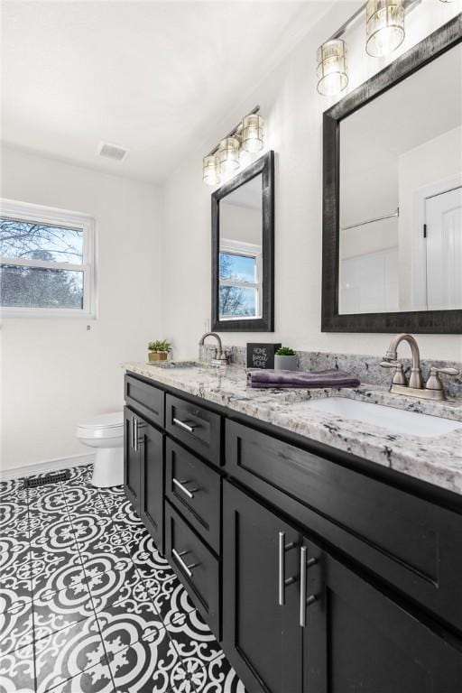 bathroom featuring a wealth of natural light, toilet, vanity, and tile patterned flooring