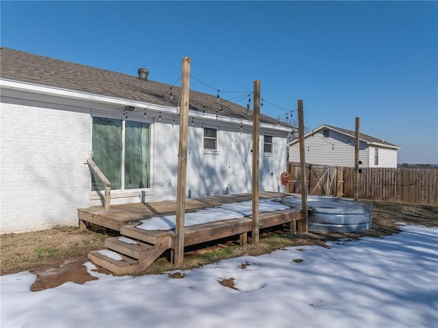 snow covered back of property featuring a wooden deck