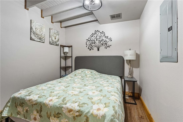 bedroom with hardwood / wood-style floors, beamed ceiling, and electric panel